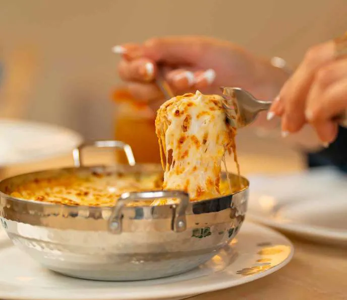 Baked cheese pulled in one long ribbon from a copper pot